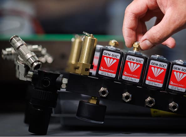 Close-up of a hand adjusting a GEM-SOL valve on a flow control manifold.